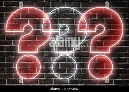 Three neon question marks on brick wall Stock Photo