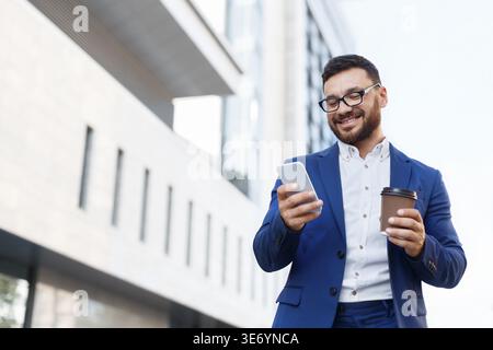 Cheerful businessman reading message on mobile phone Stock Photo