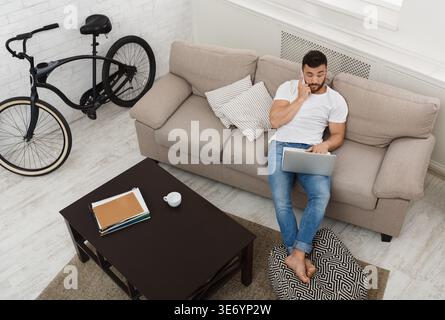 Businessman sitting at home and using smartphone for communication Stock Photo