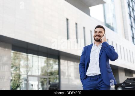 Happy smart businessman talking on phone outdoor at building Stock Photo
