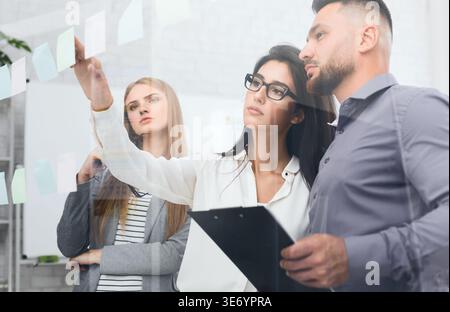 Discussing plans. Business people sticking adhesive notes Stock Photo
