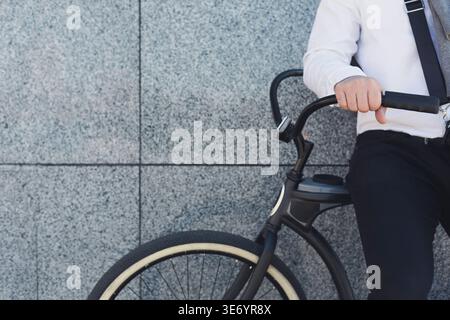 Businessman standing near his bicycle against grey background Stock Photo