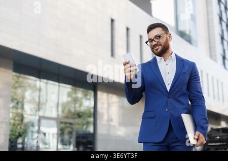 Cheerful businessman reading message on mobile phone Stock Photo