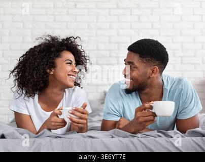Happy black couple drinking coffee in bed Stock Photo