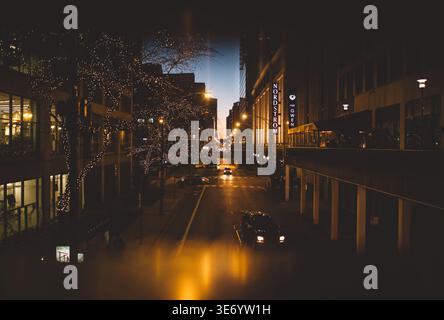 Rainy city street at dusk with reflections between tall buildings Stock Photo