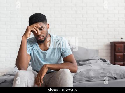 Young depressed black man sitting on bed Stock Photo