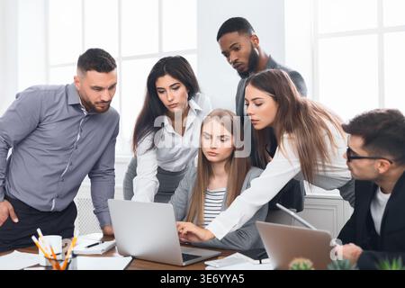 Business people gathered around laptop discussing ideas Stock Photo