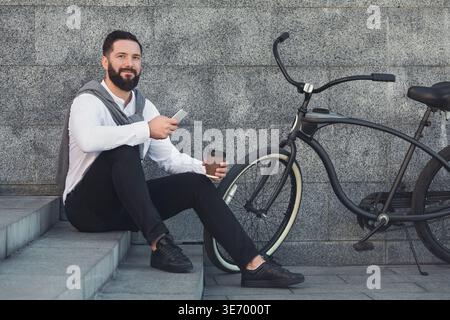 Businessman on coffee break, sitting on stairs and using smartphone Stock Photo