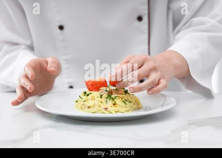 Professional chef serving tasty pasta at white marble table, closeup Stock Photo