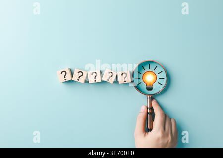 Problem Solving and Idea Discovery Concept. Hand holding magnifying glass over question mark blocks and light bulb representing creative thinking, Stock Photo