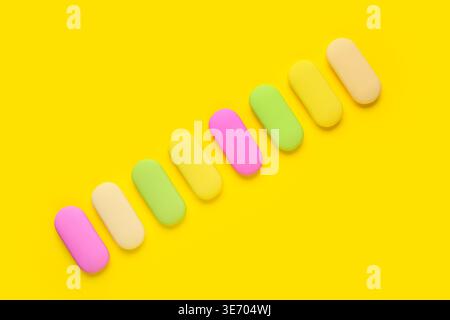 Many colorful rubber erasers on yellow background Stock Photo
