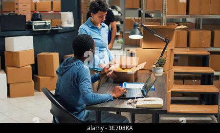 Team of startup partners doing quality control on products from storage room, checking cardboard packages of stock. Young entrepreneurs preparing goods in boxes, distribution orders. Stock Photo