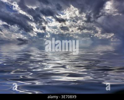Background of stormy sky with sunrays between clouds reflected in smooth wavy ocean to illustrate flooding or climate change Stock Photo