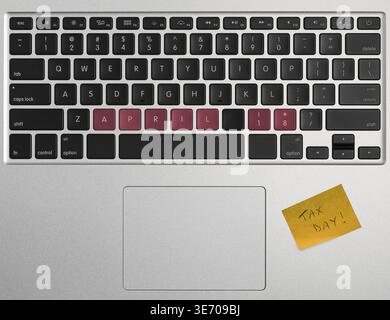 Laptop computer keyboard spelling out April 18 2017 as Tax Day with yellow sticky note as a reminder Stock Photo