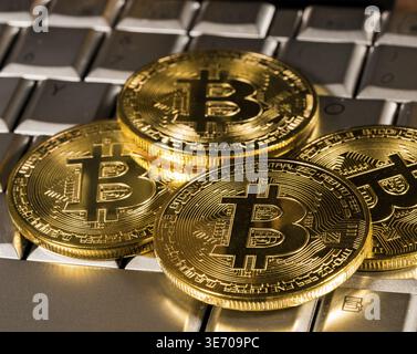 Bitcoin coin on a silver keyboard on a computer to illustrate blockchain and cyber currency Stock Photo