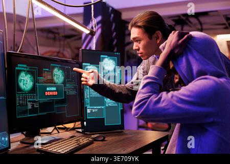 Unhappy hackers failing to crack password while breaking into computer network. Two disappointed criminals getting access denied while hacking website and attempting to pass security system Stock Photo