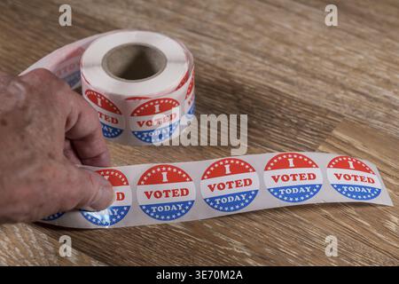 Large roll of I Voted Today stickers ready for voters in the US elections with senior mans hand Stock Photo