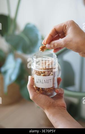 Hands holding jar of walnuts in a kitchen setting Stock Photo