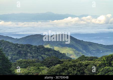 View west from Monteverde resort at sunrise over the hills towards Pacific ocean with sun breaking through clouds Stock Photo