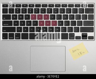 Laptop computer keyboard spelling out April 18 2017 as Tax Day with yellow sticky note as a reminder Stock Photo
