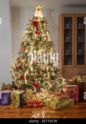 Interior of modern home with christmas tree decorated and illuminated and wrapped presents and gifts under the tree Stock Photo