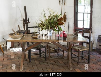 Old fashioned colonial kitchen table chairs food and apples in white room Stock Photo