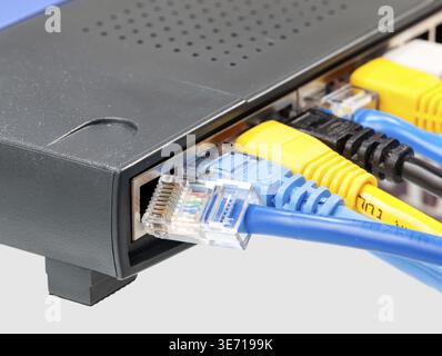 Macro shot of plugs on cat5e cables of many colors isolated against white background plugged into router Stock Photo