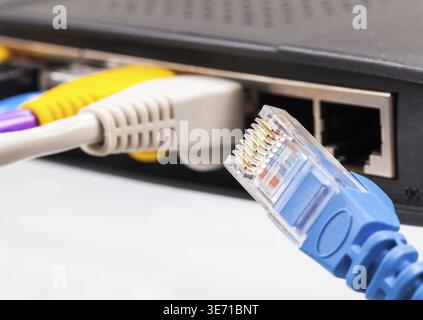 Macro shot of plugs on cat5e cables of many colors isolated against white background plugged into router Stock Photo