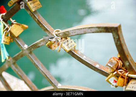 Venice, Italy - February 04, 2024: Metal railing adorned with love locks and colorful ribbons near water, showcasing inscriptions on padlocks in a rom Stock Photo