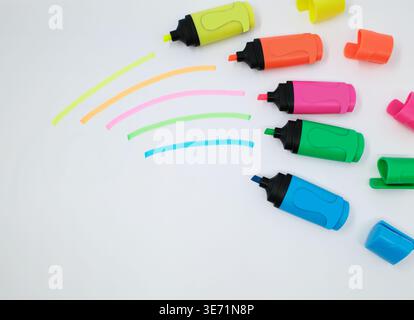Colorful highlighters are placed on a white background. The markers include yellow, orange, pink, green, and blue, each with a black base and cap. Str Stock Photo