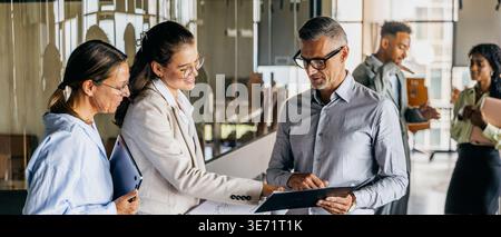 Black, white, asian manager reviewing contracts with colleague Stock Photo