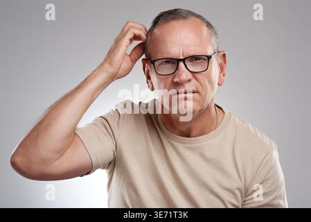 Doubt, portrait and scratching head with man in studio for confusion, question or uncertainty. Glasses, solution and thinking with mature person on Stock Photo