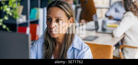 Concentrated woman analyzing digital data in sleek office environment Stock Photo