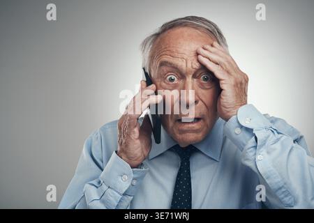 Phone call, financial advisor and man in studio, shocked and frustrated on gray background. Mature person, announcement or investor with cellphone Stock Photo