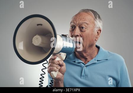Shouting, danger or old man in studio with megaphone, alert or announcement for attention. Warning, voice or senior person on white background with Stock Photo