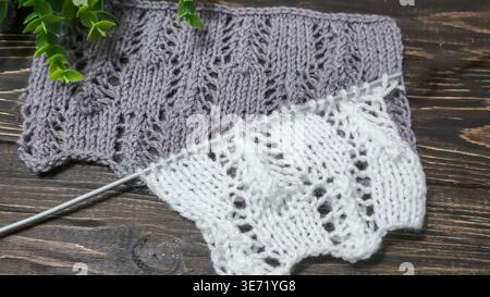 A raised openwork pattern knitted with colored yarn on a wooden background. Knitting tutorial. Fabric texture. Stock Photo