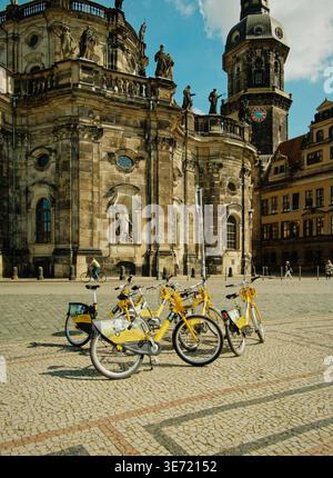 Yellow Bicycles By Cathedral. Sunny Cobblestone Street With Brightly Colored Rental Bicycles In Row Stock Photo