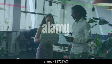 Discussing colleagues in casual attire reviewing code on laptop and tablet in open-plan office. Collaboration, coworking, modern, minimalist, teamwork Stock Photo