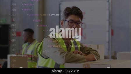 Leaning mature Korean man in hi-vis vest inspecting stacked boxes at loading bay, code overlay. Warehouse, logistics, teamwork, pallets, industrial, s Stock Photo