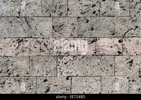 Close up of natural stone wall with irregular block pattern and rough porous surface creating organic texture background Stock Photo