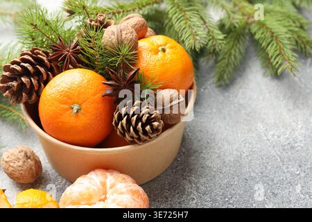 Tangerines with cones, anise stars and fir tree branches on grey table, closeup Stock Photo