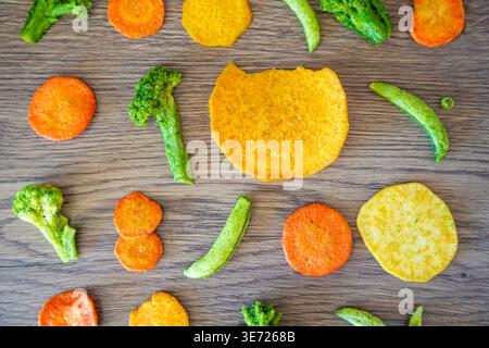 Seamless pattern of vegetable chips with broccoli carrot peas and sweet potato on wooden background. Healthy snack texture and clean eating concept. Stock Photo