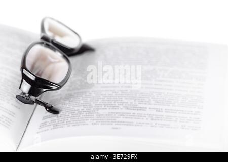 One opened book pages with glasses on top front view isolated white background macro Stock Photo