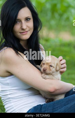 Young woman with Labrador puppy in her arms Stock Photo