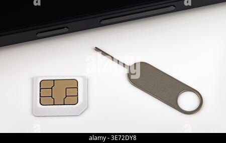 Close-up macro shot of inserting sim card with ejector tool into a smartphone Stock Photo