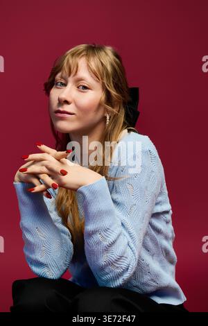 A stylish young woman poses confidently with her hands clasped. Stock Photo