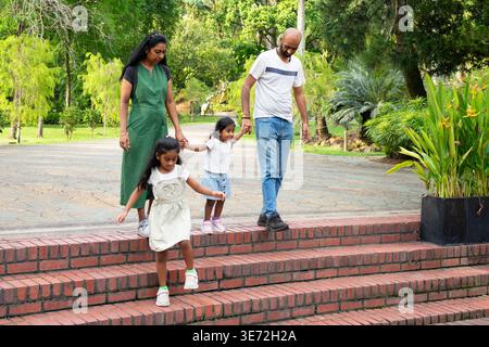 Indian family walking outdoors, holding hands and enjoying leisure time together Stock Photo