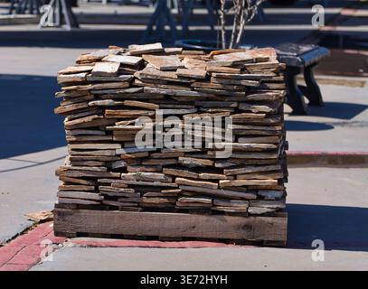 Neatly arranged stack of flat stones on a wooden pallet, suitable for landscaping or construction in an outdoor environment Stock Photo