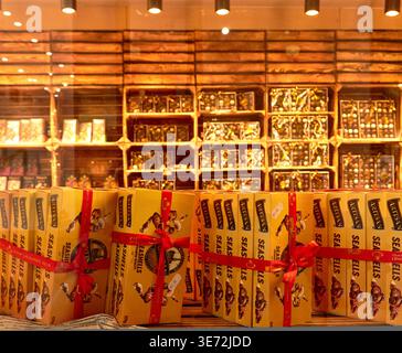 Brussels, Belgium - October 01, 2025: Interior of a chocolate boutique showcasing gift boxes tied with red ribbons and shelves stocked with various ch Stock Photo
