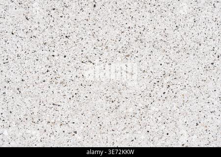 High-resolution quartz or terrazzo texture background showing a polished white surface embedded with tiny gray, brown, and black mineral pebbles Stock Photo